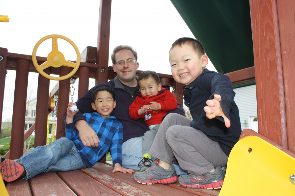 The four boys hanging out in atop the play set. 